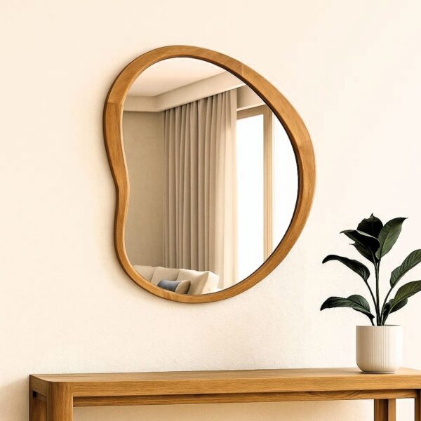 מראה אמורפית עם מסגרת עץ טבעי תלויה מעל קונסולה מעץ, בעיצוב מודרני חמים עם קווים רכים ואלגנטיים. מראה אמורפית עם מסגרת עץ טבעי