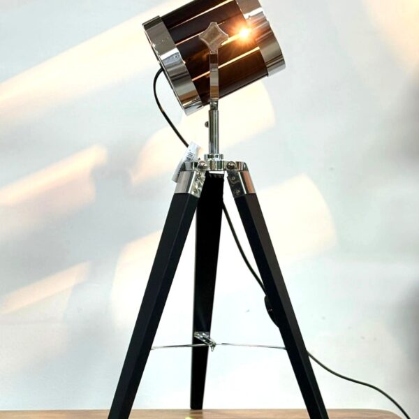 מנורת סטודיו שולחנית דגם 551949199, מבנה חצובה יציב ממתכת בגימור שחור, ראש מתכת עם חבקי כרום מתכווננים לכיוון האור, מפסק חיבור לכבל חשמל, מתאימה לשימוש כשולחן עבודה, תאורת אווירה או תאורה דקורטיבית לחללי מגורים ומשרדים. מידות: גובה 60 ס"מ.