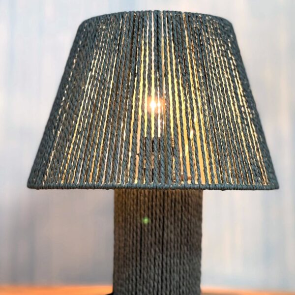 מנורת שולחן דגם 551938099 עשויה חבל טבעי בצבע אפור, גוף בעבודת קליעה ידנית, מפזרת אור אחיד וחמים, חיבור חשמל סטנדרטי עם מפסק, מתאימה לשימוש דקורטיבי בסלון, חדר שינה או פינת עבודה. מידות: 30×35 ס״מ