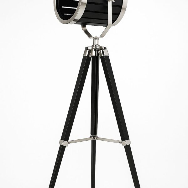 מנורת סטודיו עומדת דגם 551952399 בעיצוב חצובה מעץ צבוע שחור עם ראש תאורה גלילי ממתכת בגימור כרום כהה, כולל ראש מתכוונן לפיזור אור מדויק, מערכת חיבור חשמלית עם מפסק הפעלה, בסיס של שלוש רגליים ליציבות מרבית. גובה: 152 ס״מ